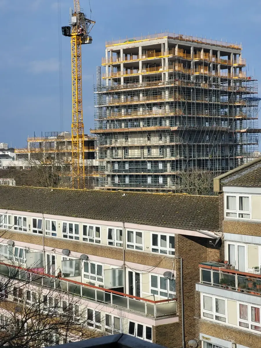 High-rise building under construction with scaffolding and a tower crane