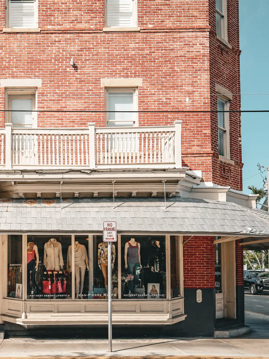 Corner of a red brick building with a balcony above a ground-floor shop